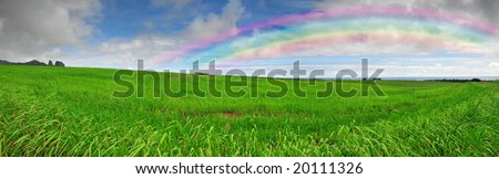 Beautiful lush green meadows under a blue sky with a rainbow circling the horizon - Large panorama image ideal for huge banners