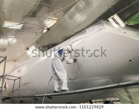 Painters are spraying paint to repair Sailing yacht at shipyard , factory in Phuket,Thailand