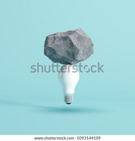 Stone put on White light bulb floating on blue background. minimal creative idea concept.