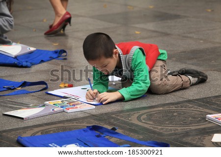 HANOI, VIETNAM - MAR 30, 2014: Unidentified Asian children learning to draw on the ground at a park near Hoan Kiem lake in Hanoi capital, Vietnam. Hanoi is known as a \