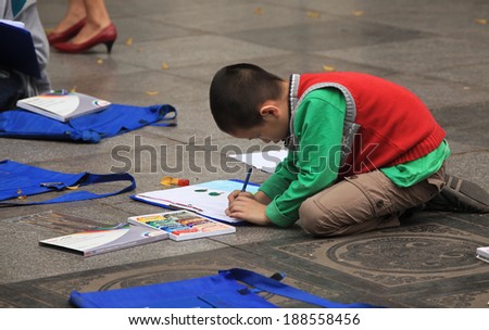 HANOI, VIETNAM - MAR 30, 2014: Unidentified Asian child learning to draw on the ground at a park near Hoan Kiem lake in Hanoi capital, Vietnam. Hanoi is known as a \