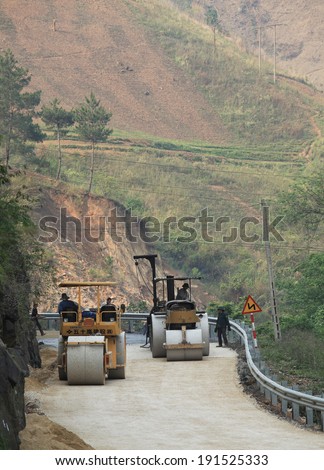 YEN BAI, VIETNAM - APR 11, 2014: Rollers machines working on an under-construction mountain road in Mu Cang Chai district, north west Vietnam. Mu Cang Chai is one of the poorest area of the country.