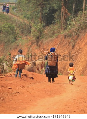 YEN BAI, VIETNAM - APR 12, 2014: Unidentified Vietnamese minority group carrying packages of grain on back on the way to their village. Agriculture is one of the most important industry in Vietnam.