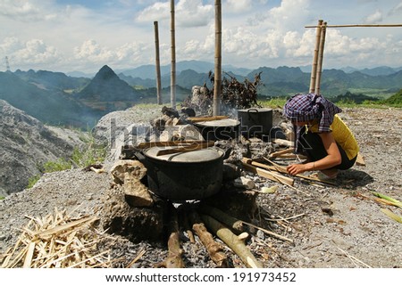HOA BINH, VIETNAM - JUL 1, 2010: Unidentified Vietnamese Thais woman cooking rice outdoor in a traditional way under the sunlight in a mountain area, north west of Vietnam.