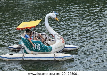 HANOI, VIETNAM - JUL 13, 2014: Unidentified Vietnamese children paddling a swan boat on the lake of Thu Le park, Hanoi capital. The park also has a zoo.