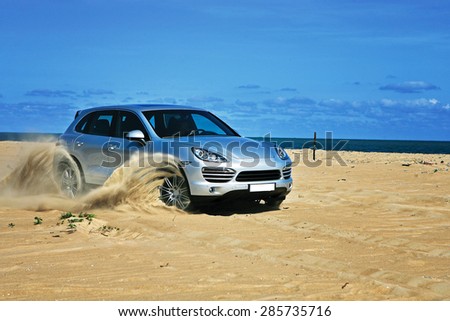 Vung Tau, Vietnam - April 20, 2012: A luxury sport car running on sand terrain of the beach side under the sunlight in a off-road test drive.