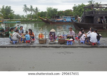Hoi An, Vietnam - Jun 20, 2015: Vietnamese food vendor selling traditional cakes and noodles on the bank of Hoai river in Hoi An ancient town. Hoi An is recognized as a World Heritage Site by UNESCO.