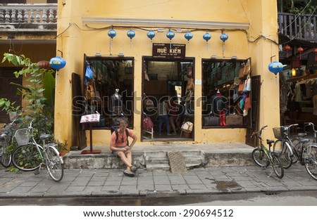 Hoi An, Vietnam - Jun 20, 2015: An European visitor taking a rest in front of a leather costume store in Hoi An ancient town. Hoi An is recognized as a World Heritage Site by UNESCO.