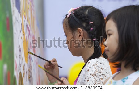 Hanoi, Vietnam - Sep 19, 2015: Asian children drawing images and writing their wishes by paint brush on a wall in occasion of traditional Full Moon Festival (mid August of lunar calendar).