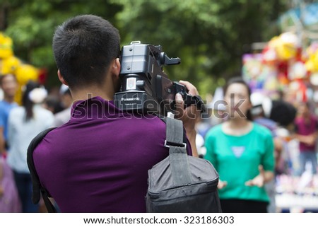 Hanoi, Vietnam - Sep 27, 2015:Unidentified Asian cameraman filming a female journalist on site to report daily life activities at Hang Ma old quarter street in Hanoi capital.