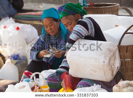 Lao Cai, Vietnam - Oct 17, 2015: Vietnamese Hmong women selling traditional wine in canes at low price at Bac Ha weeky flea market, north west of Vietnam.