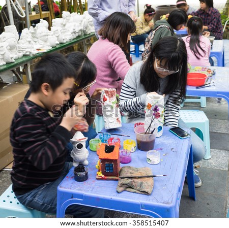 Hanoi, Vietnam - Jan 1, 2016: Asian children painting clay toys with colorful water at a playground in Ecopark residential villa and building, Hanoi capital city.