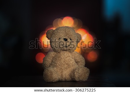 bear toy sitting on old wood and bokeh background