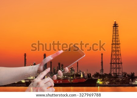 double exposure of female hand hold and touch screen smart phone, on oil refinery blurred background.
