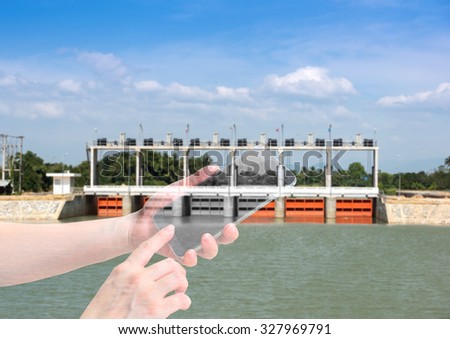 double exposure of female hand hold and touch screen smart phone, on small dam blurred background.