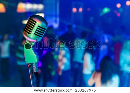 Color professional studio microphone in a night club. There are dancing people on background.