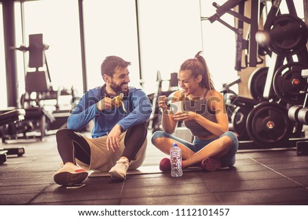 Young couple at gym eating healthy food after exercise.