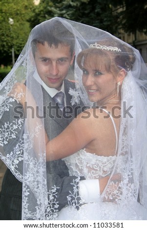 bride and groom under the veil looking at camera