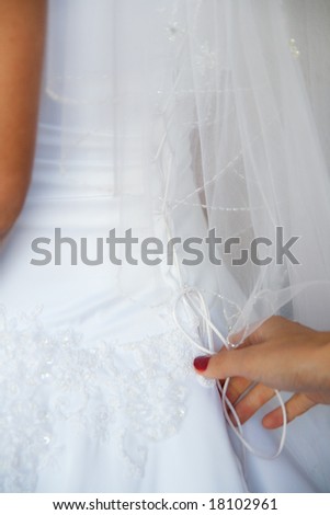 Female hands tightening a corset to the bride