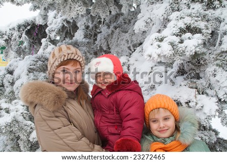 Happy family (mother with small girls) in winter snow covered city park