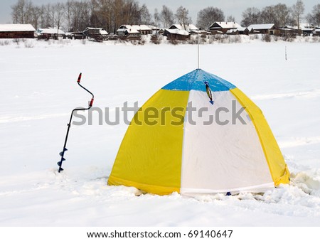 tent and a drill for ice on the river ice during the winter fishing