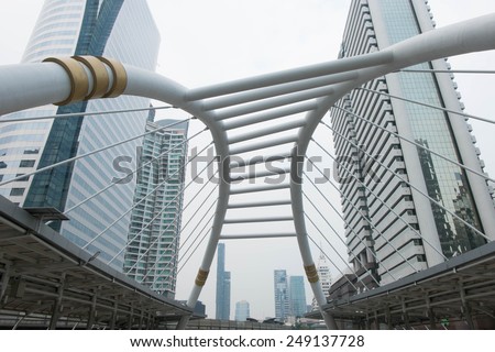 SATHORN ROAD, BANGKOK - JAN 31, 2015: High-Rise buildings with little fog and a sky walk at Sathorn-Narathiwas intersection. Sky walk is the connecting walkway between sky train and rapid bus.
