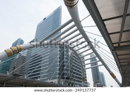 SATHORN ROAD, BANGKOK - JAN 31, 2015: High-Rise buildings with little fog and a sky walk at Sathorn-Narathiwas intersection. Sky walk is the connecting walkway between sky train and rapid bus.