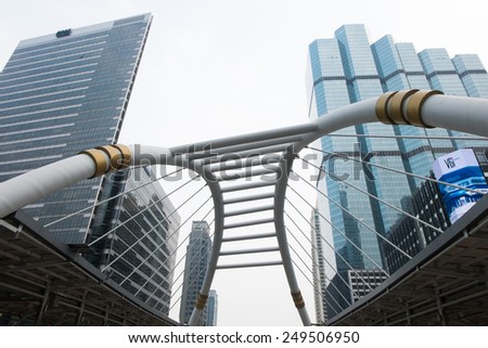 SATHORN ROAD, BANGKOK - JAN 31, 2015: High-Rise buildings with little fog and a sky walk at Sathorn-Narathiwas intersection. Sky walk is the connecting walkway between sky train and rapid bus.