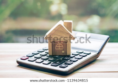 House is placed on the calculator. Imagine calculating to buy a home. planning savings money of coins to buy a home concept for property, mortgage and real estate investment.to buy a house.