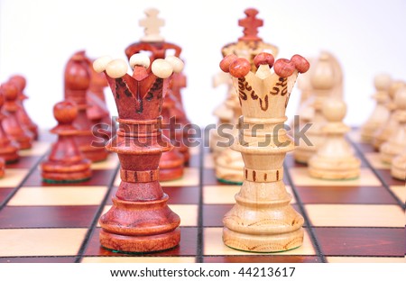 Closeup on two chess queens, pieces blurry in background