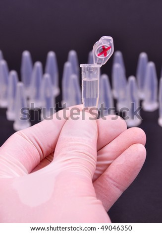 Hand in glow holding a research tube, other tubes in blurry background
