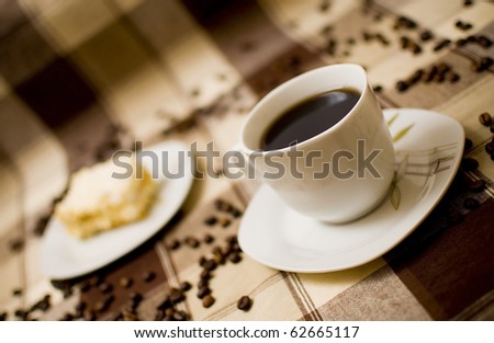 Coffee cup and cake on table, cake in blurred background