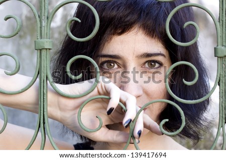 Brunette woman behind bars in the garden