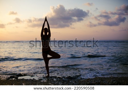 Vrikshasana tree pose from yoga by woman silhouette on sunset