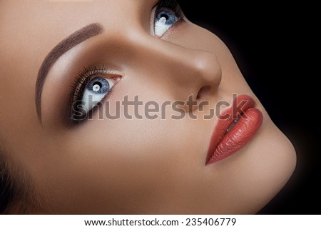 Beauty Close-up Portrait of Beautiful Sexy Woman Model with Brown Fashion Eyes Make-up and Red Lips on Black Background