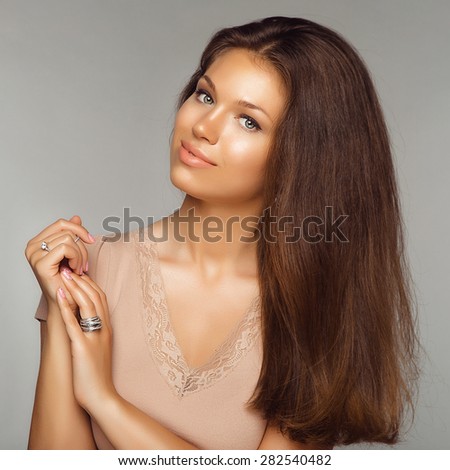 Portrait of Young Beautiful Brunette Woman with Jewelry Ring. Healthy Long Hair and Clean Skin on Grey Background