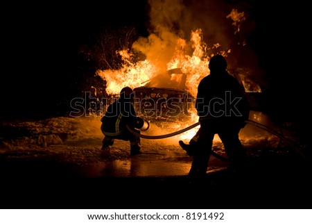 Firemen fighting a flaming car after an explosion