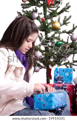 Girl opening a Christmas present with a traditional seasonal scenery in the background