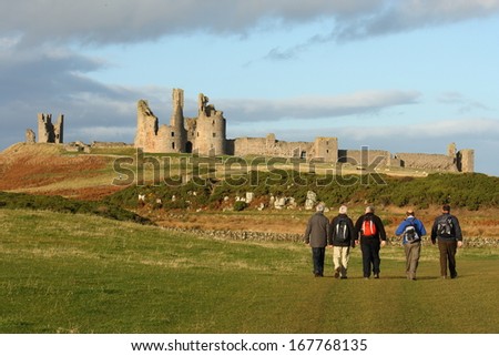walkers at Dunstanburgh castle in Northumberland, UK