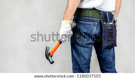 Carpenter man stand in carpentry shop with concrete background and holding hammer on hand.Labor market of joiner and craftsman concept.Free space.