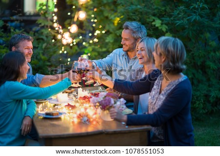 One summer evening, friends in their forties gathered around a table in the garden lit by luminous garlands. They toast with their glasses of wine