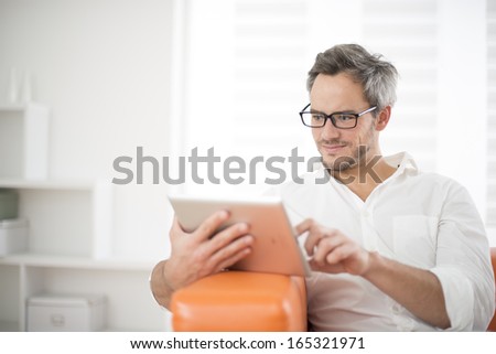 handsome man surfing on tablet on a couch handsome man surfing on tablet on a couch