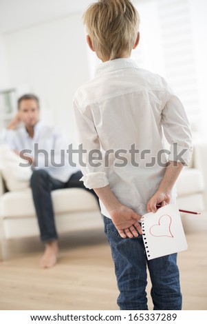boy offering a drawing heart to his father