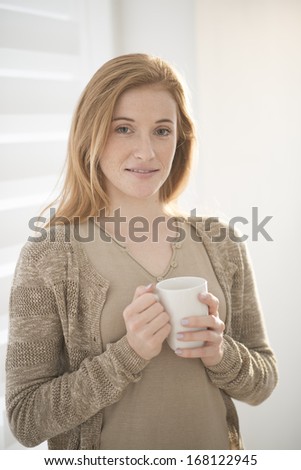 closeup of an attractive redhead young woman with a mug