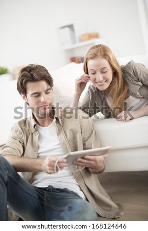 young couple sharing music on tablet