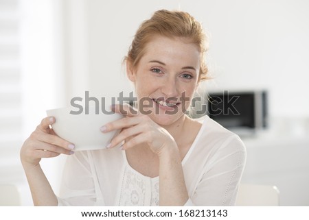 closeup young woman drinks in a big mug at breakfast