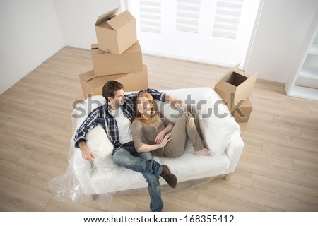 smiling couple lying on sofa in new home
