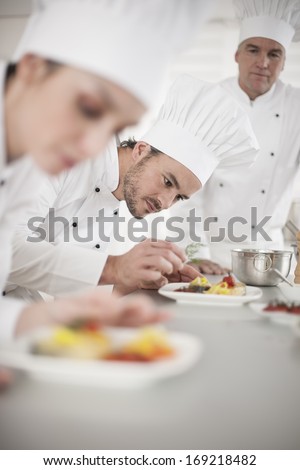 Team preparing dishes in a professional kitchen focus on a cook