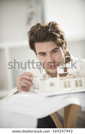 man studying a construction project with a model house