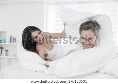 pillow fight for a young couple in bed